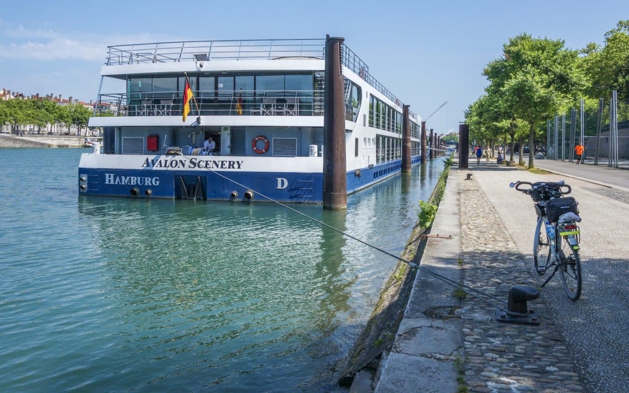 a blue and white boat docked next to a sidewalk